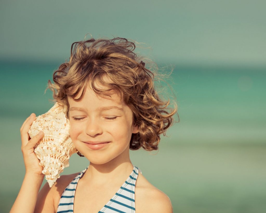 child listening to a seashell